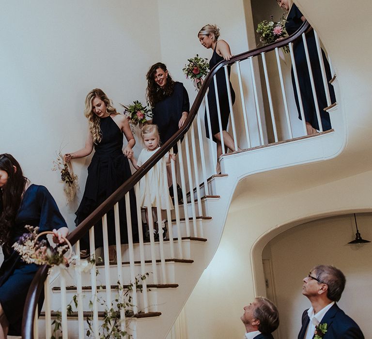 Bridal party walking down the stairs in navy blue bridesmaid dresses 