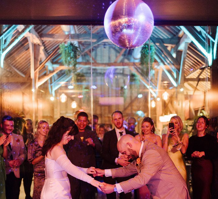 The bride and groom have their first dance together under the disco ball 