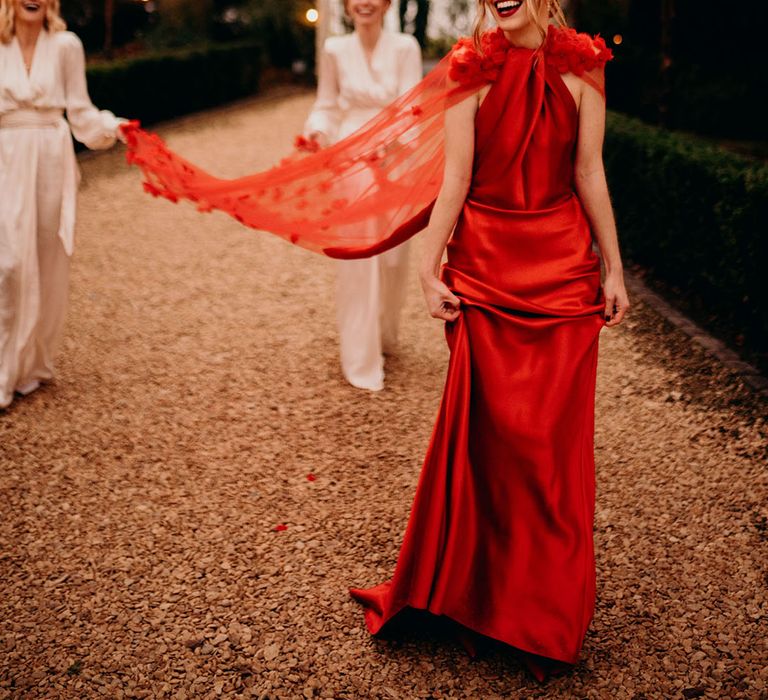 Bride in red satin wedding dress for festive wedding with bridal cape 