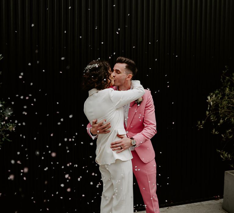 The bride in a white bridal suit embraces the groom for cute wedding photo 