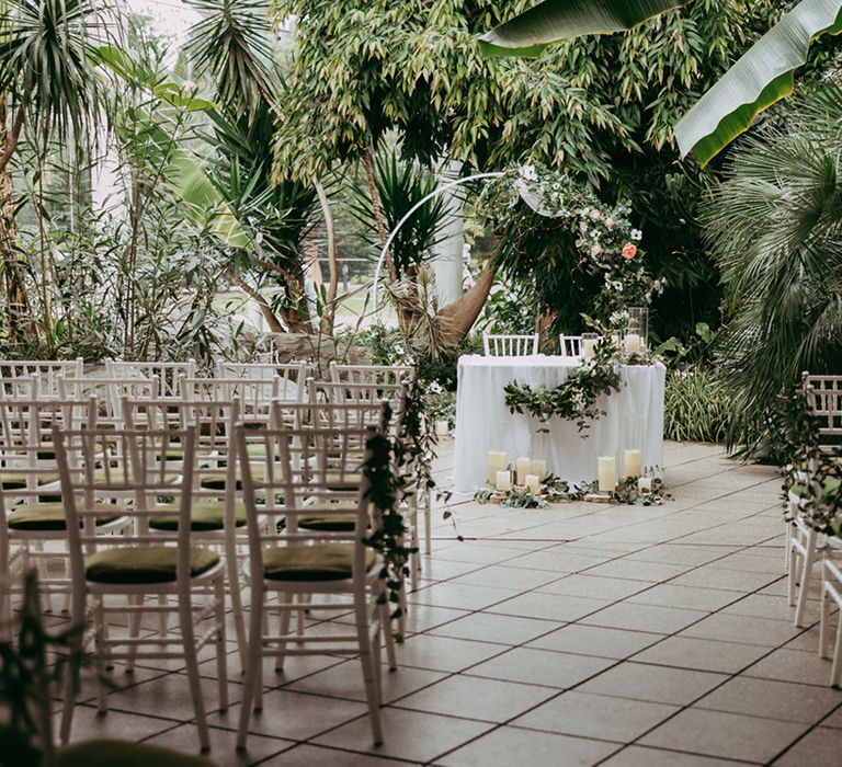 The Riverside Glass House botanical glasshouse wedding venue with a sweetheart table and white and green floral arch decoration 