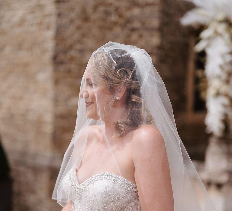 Bride wearing white veil carrying a white orchid wedding bouquet in embellished mermaid wedding dress 