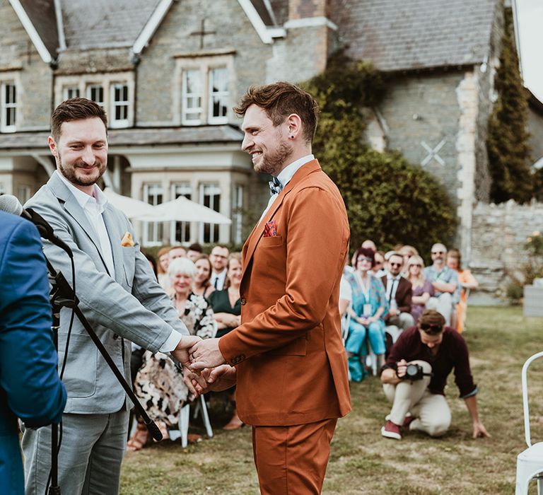 Wilde Lodge wedding with the two grooms holding hands for their outdoor wedding 