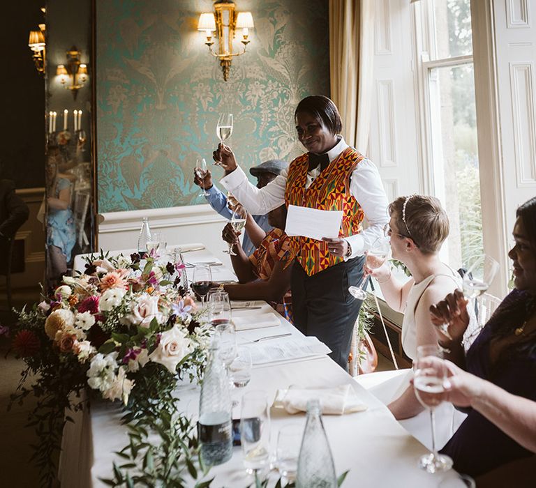 Bride in Ghanian waistcoat standing up at wedding breakfast to read out wedding speech 