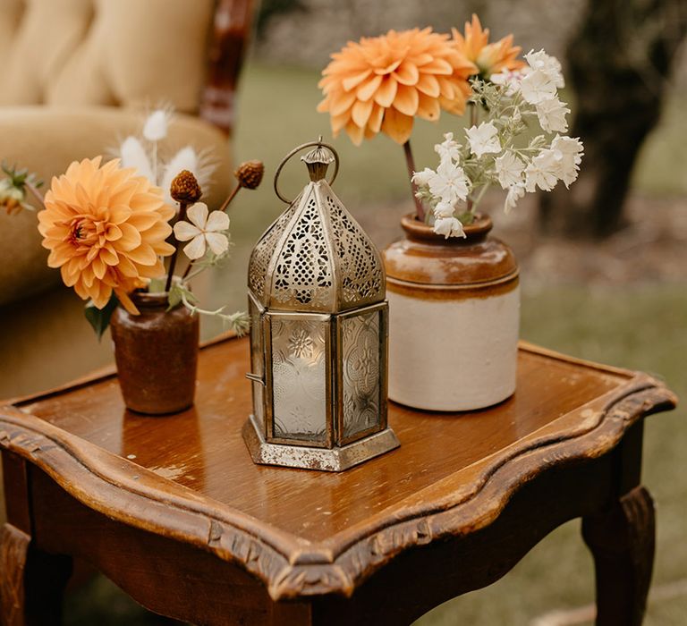 Simple minimalist wedding decor with vases filled with yellow dahlias and metal candle lanterns 