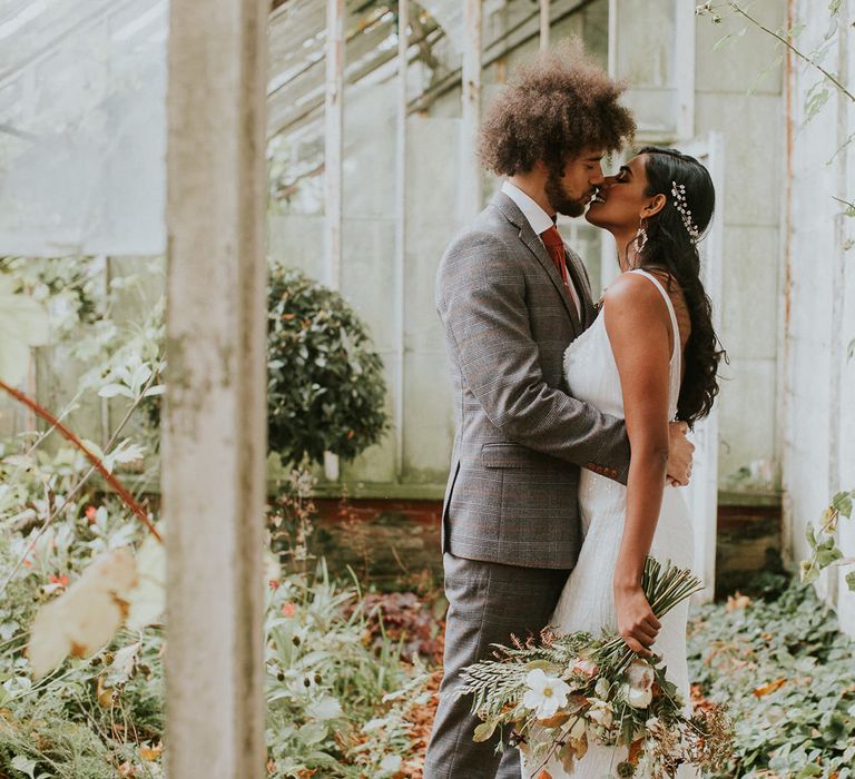 Bride and groom kissing in the glasshouse at Hooton Pagnell Hall 