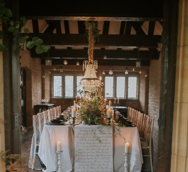 Intimate wedding table at Hooton Pagnell Hall with chandelier installation and script table cloth 