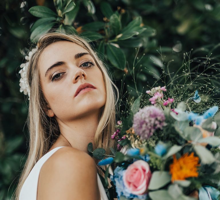 Bride with soft shimmer makeup poses with her bright and colourful bouquet