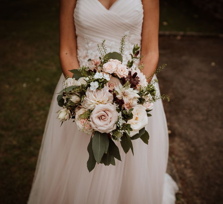 Bride in blush wedding dress holding a pink flower wedding bouquet with roses and dahlias 