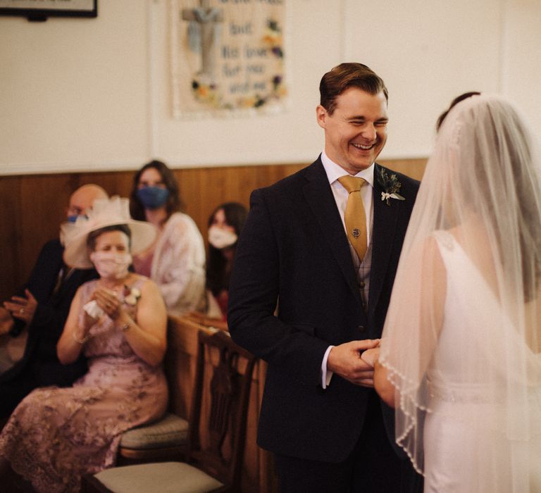 Bride & groom hold hands during wedding ceremony