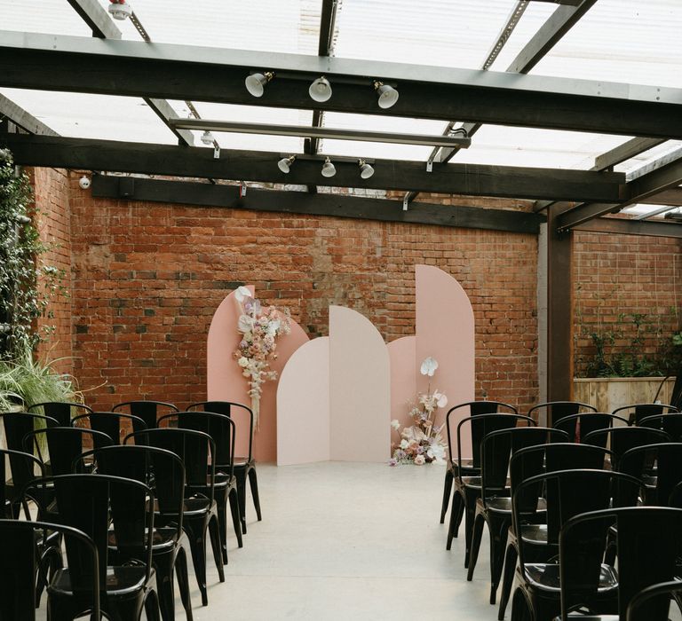 Aisle at The Shack Revolution wedding venue with black metal chairs and pink altar structure. 