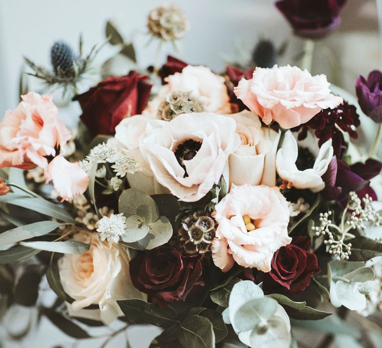 White anemone and pink and red rose wedding bouquet with thistle