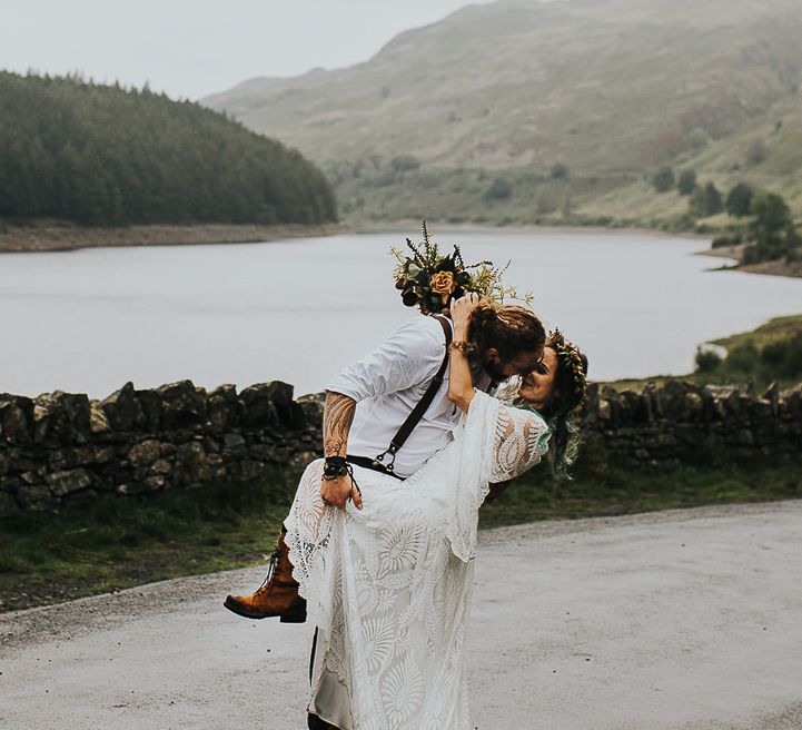 Groom kisses bride holding floral bouquet after wedding ceremony