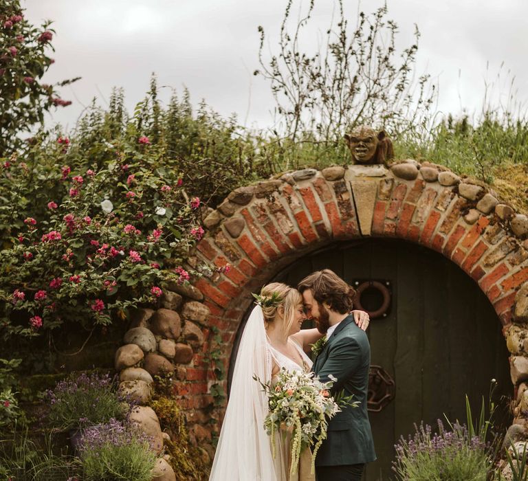 Bride & groom stand together and embrace outdoors