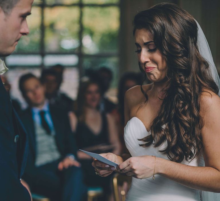 Emotional bride on her wedding day holding order of service next to her new husband 