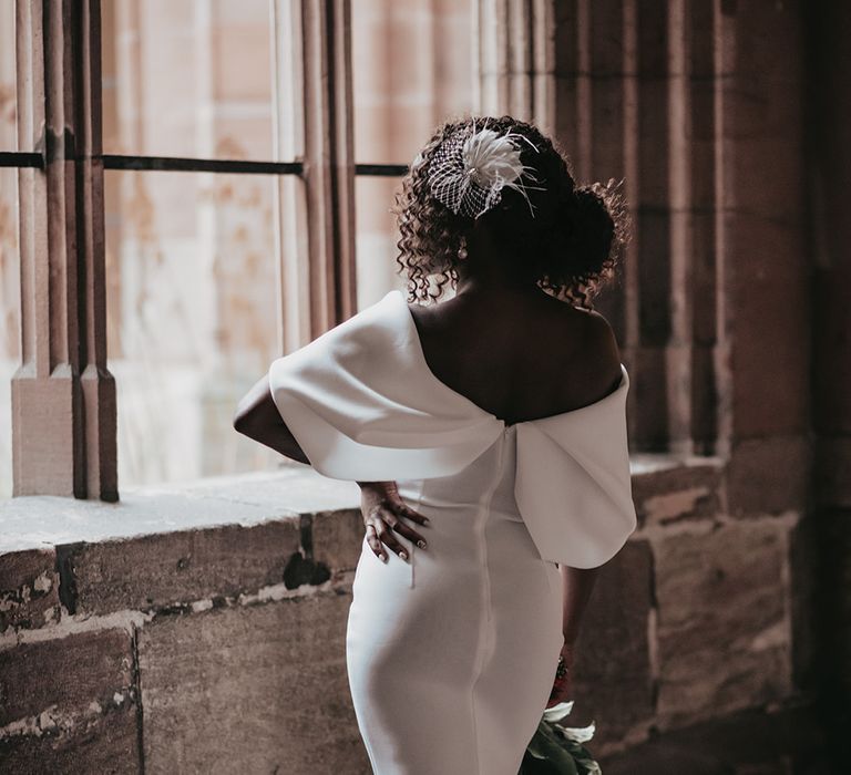 Bride poses whilst wearing mini wedding dress with off the shoulder detailing