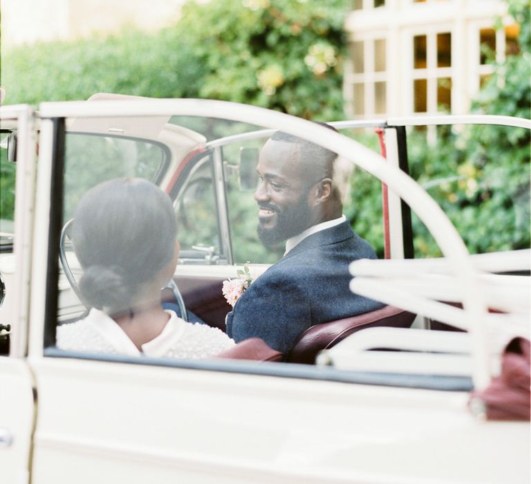 Bride and groom sitting in a vintage white Morris Minor car