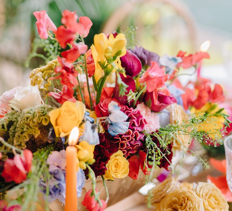 Close up shot of table bouquet featuring bright and bold blooms with green foliage