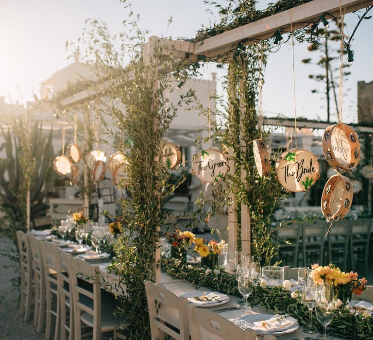 Beautiful wedding table set up with olive leaf foliage and garlands and hanging personalised tambourines 