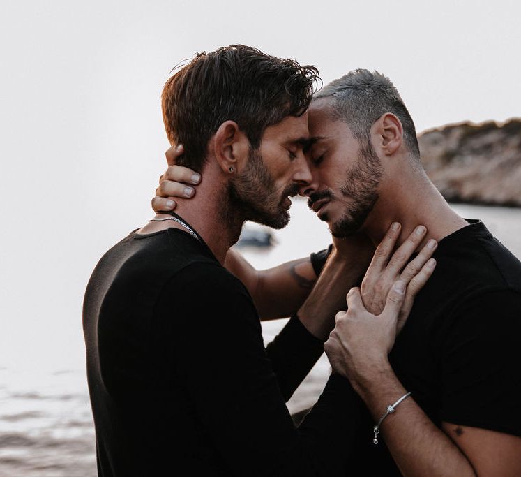 Grooms tenderly embrace and go to kiss during engagement session