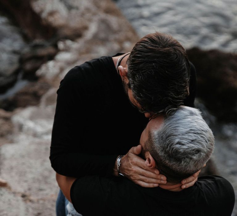 Grooms passionately kiss on the rocks of Ibiza 