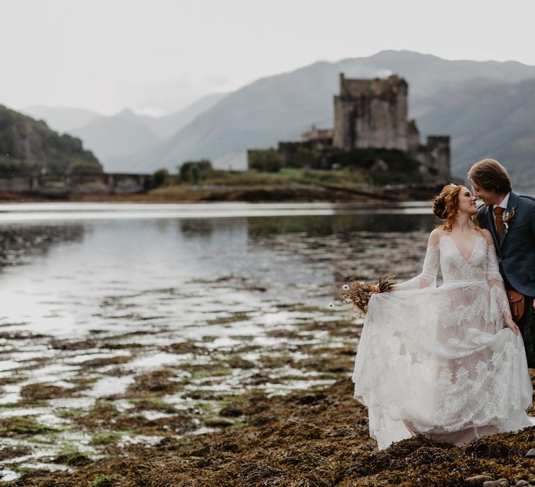 Bride & groom kiss with the sea in the background and castle