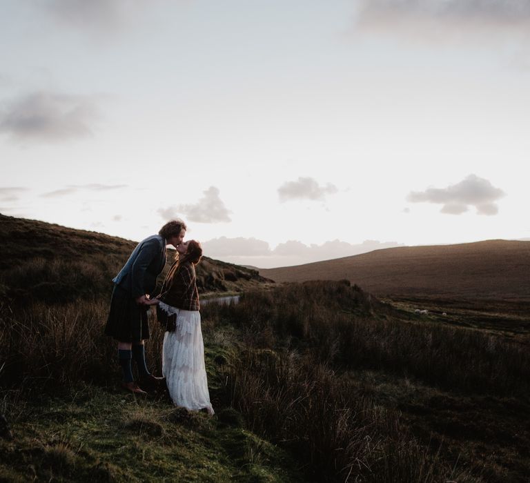 Bride & groom stand together on the hillside 