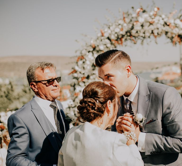 Groom kissing his mother on the forehead before getting married