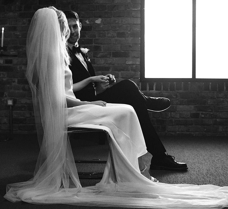 Bride in a cathedral length veil sitting during the church wedding ceremony 