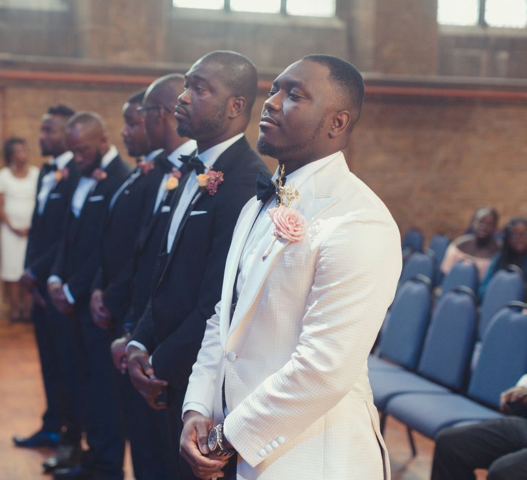 Groom awaits bride as he stands with his ushers on wedding day