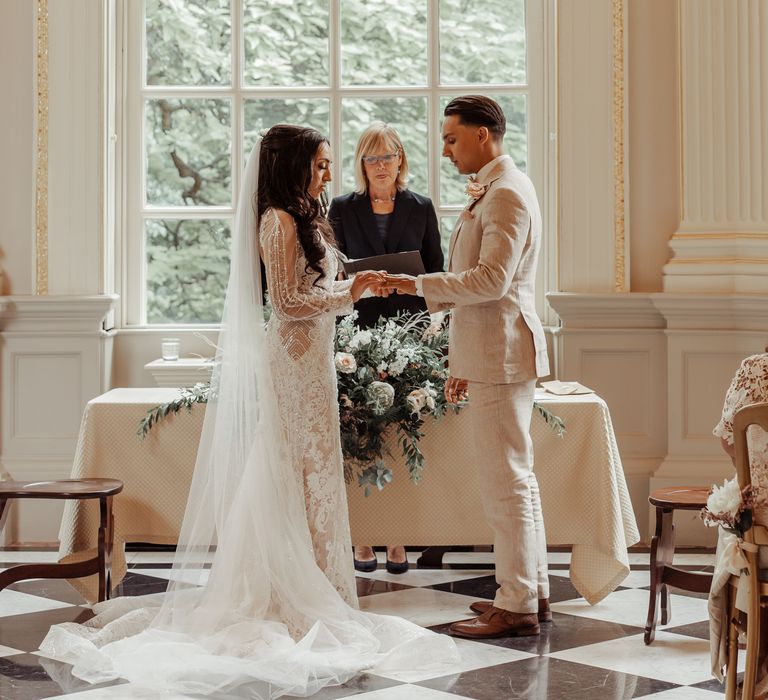 Bride & groom stand in front of large window during their wedding ceremony