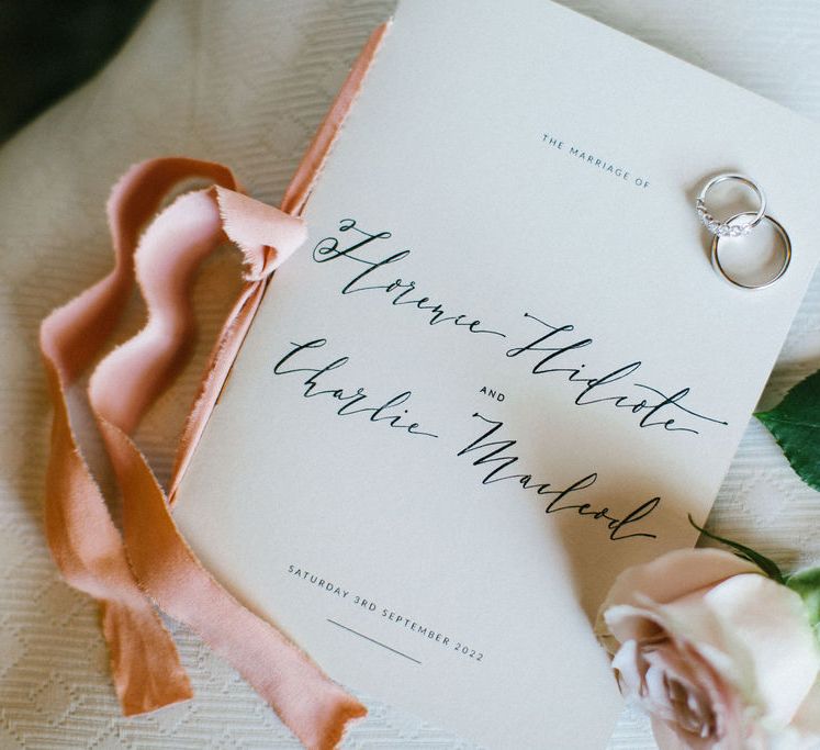 Classic wedding invitation with script font and pink ribbon detail 