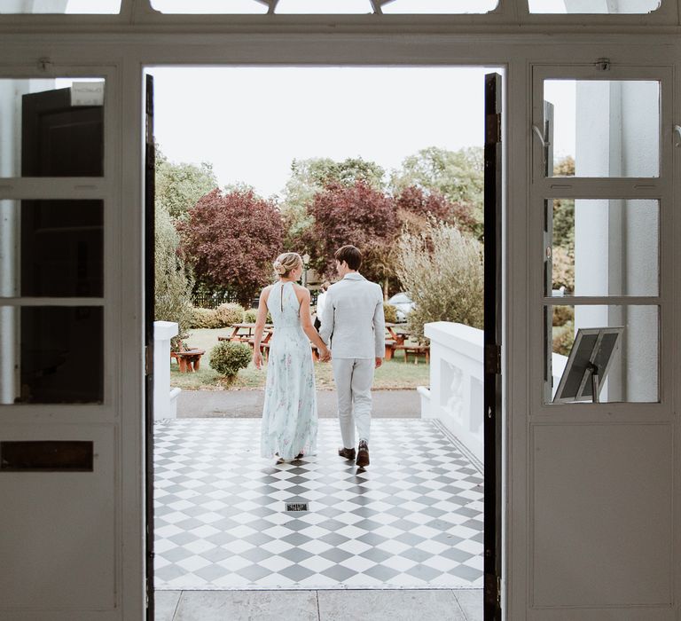 Bride & groom walk hand in hand on the day of their wedding as they leave the Belair House