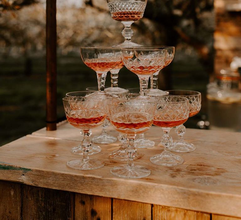 Tower of crystal cut coupe glasses filled with pink champagne 