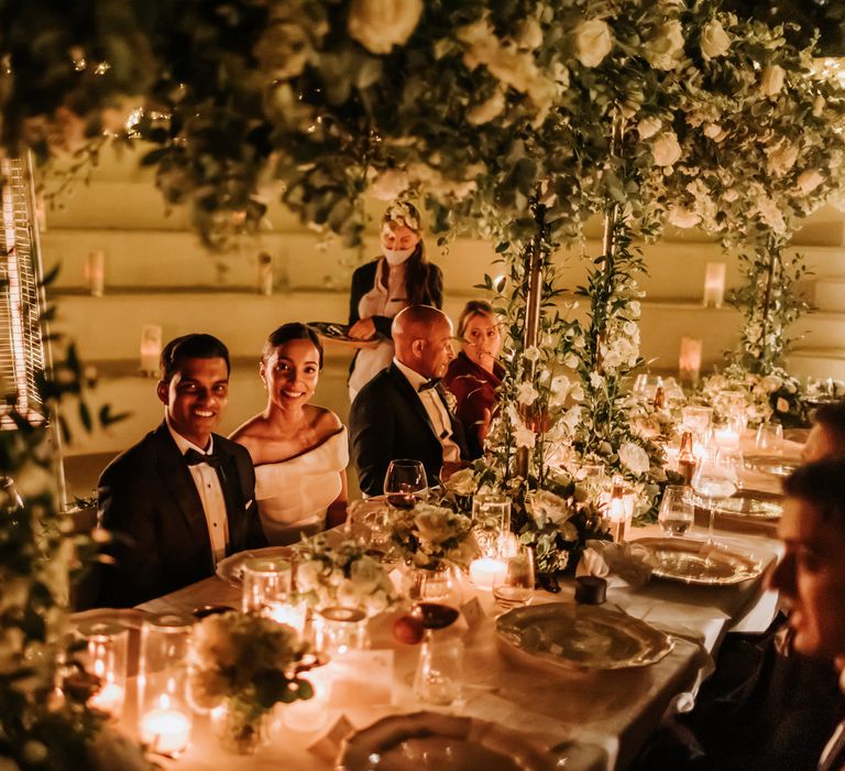 Bride & groom sit down for fairy light and florally decorated reception dinner in amphitheatre in Greece | Hannah MacGregor Photo & Film