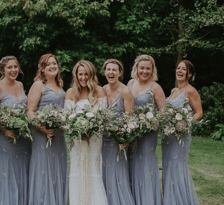 Bride in Grace Loves Lace bardot wedding dress stands in the middle of bridesmaids in blue beaded cami bridesmaid dresses at Isle of Wight wedding with macrame wedding decor