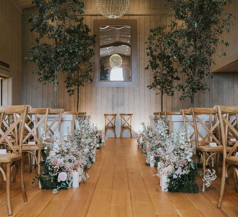 Barn wedding ceremony room at Primrose Hill Farm with wooden chairs, trees and white and pinks florals down the aisle with candles for summer wedding