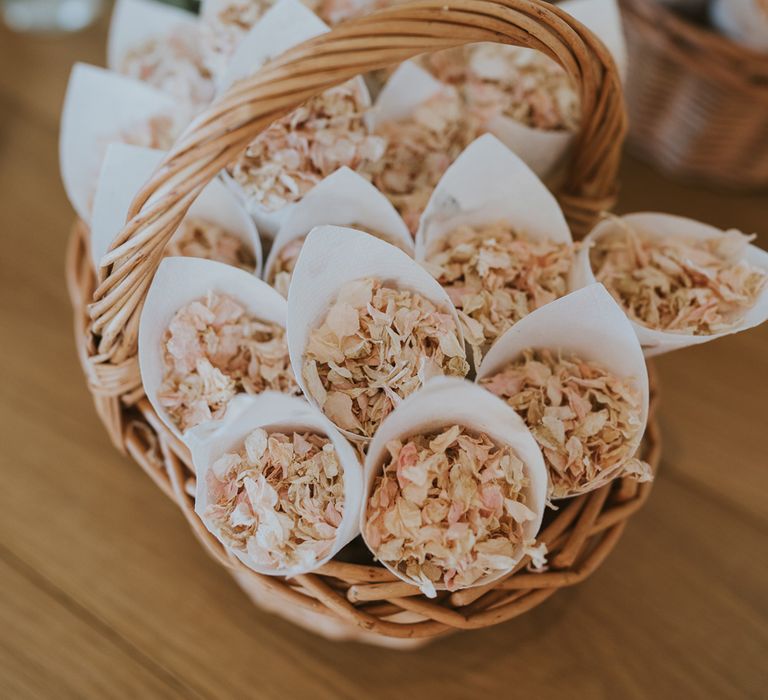 Pink and white dried petal confetti in paper confetti cones piled in wooden basket for summer wedding at Primrose Hill Farm 