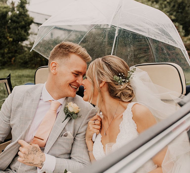 Bride and groom share a moment under umbrella on wedding day