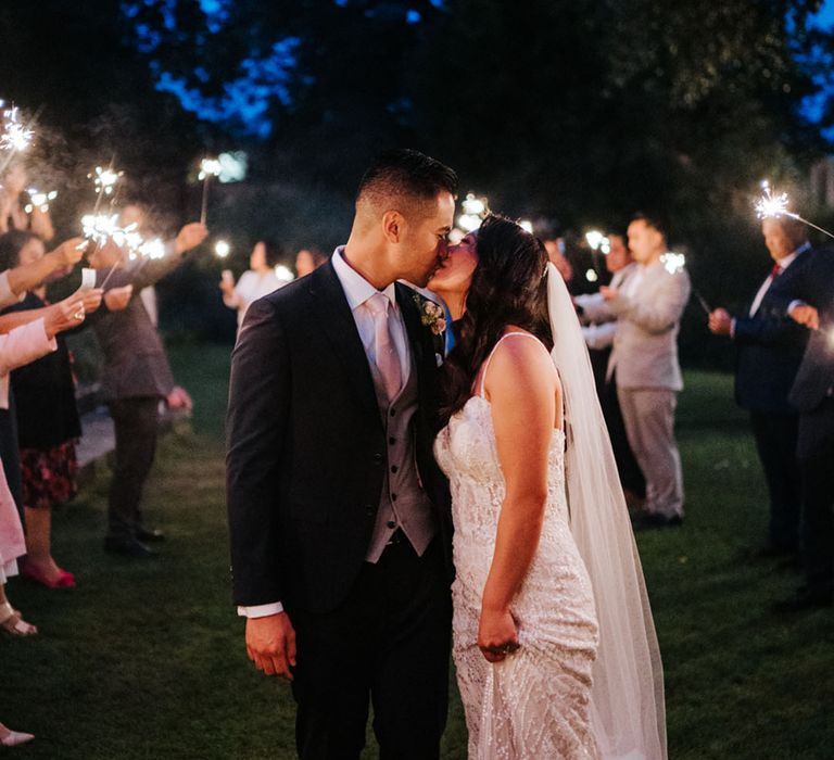 Bride and groom in a sequin wedding dress and navy suit kissing during their sparkler exit at Bingham Riverhouse Wedding 