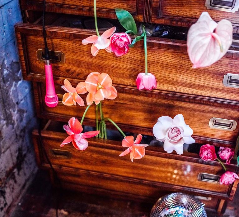 Vintage dresser filled with brightly coloured flower stems and silver disco balls 