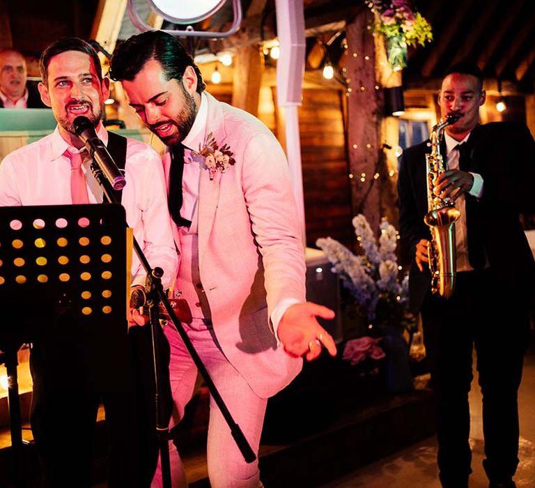 Groom in a beige three-piece suit jamming with the wedding band 