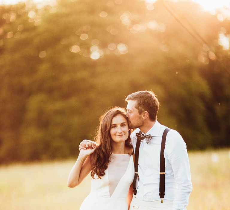 Bride & groom walk in field during golden hour on their wedding day