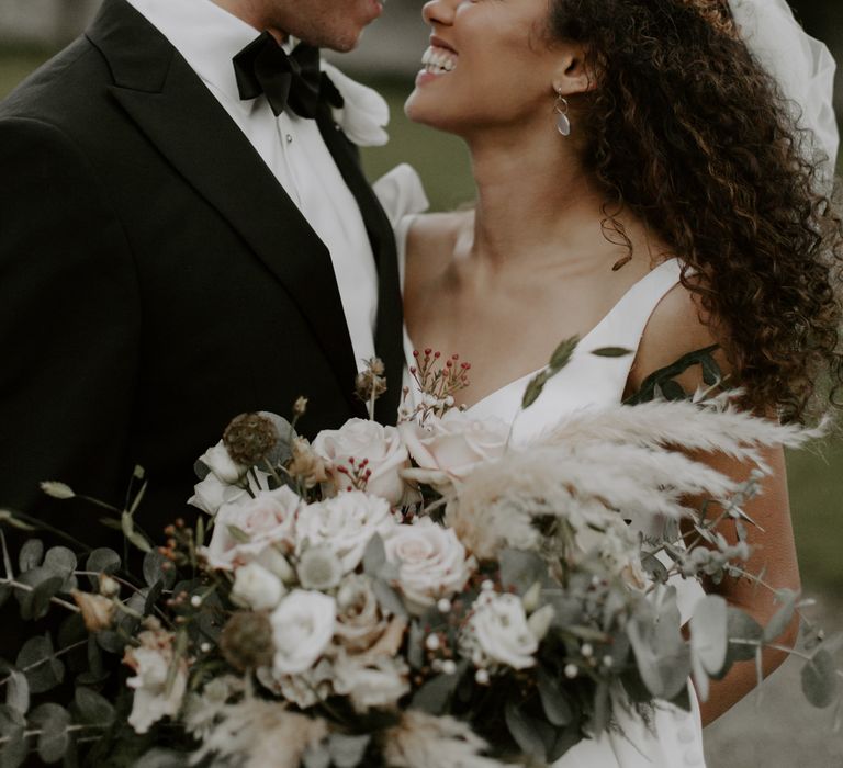 Bride & groom look toward one another as brides veil blows in the wind