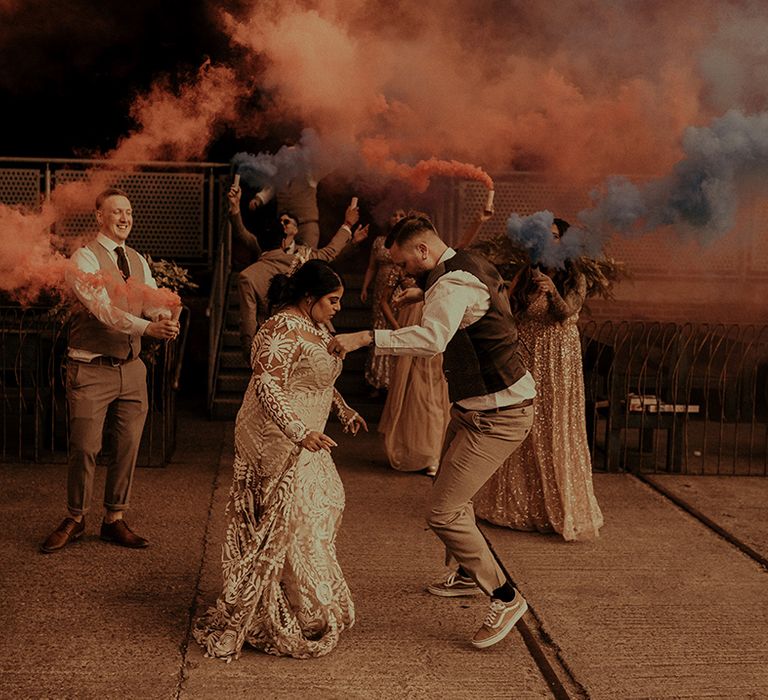 Fun smoke bomb wedding photography with bride and groom dancing surrounded by their wedding party