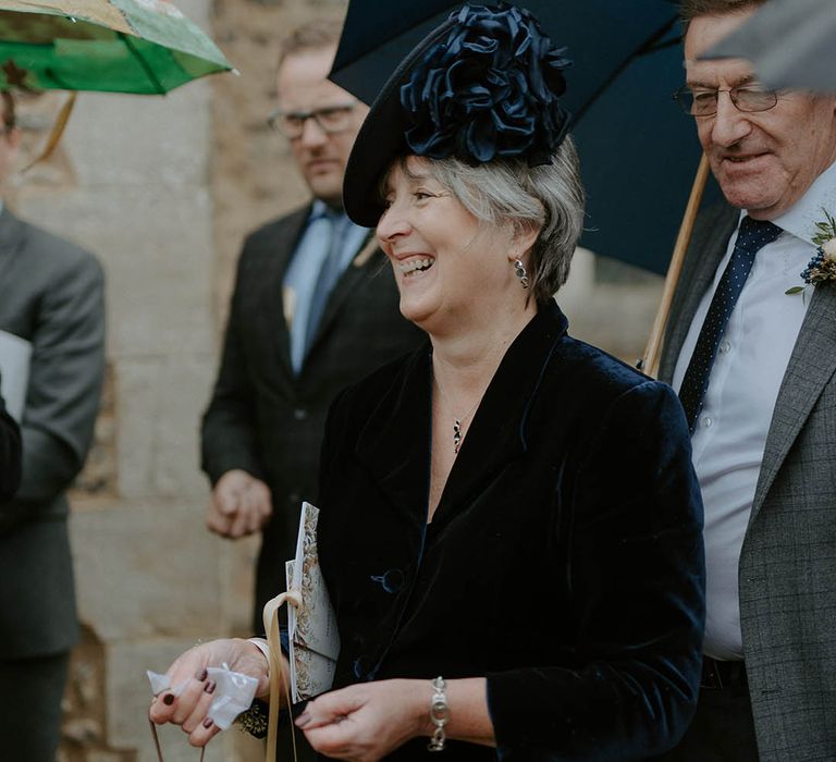 Wedding guest in navy outfit and hat with large flower detail