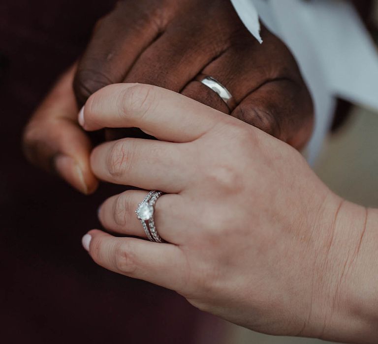 Bride & groom hold hands on their wedding day wearing wedding bands