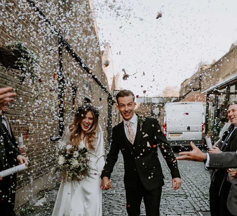 Bride & groom walk with one another through cobbled streets on their wedding day