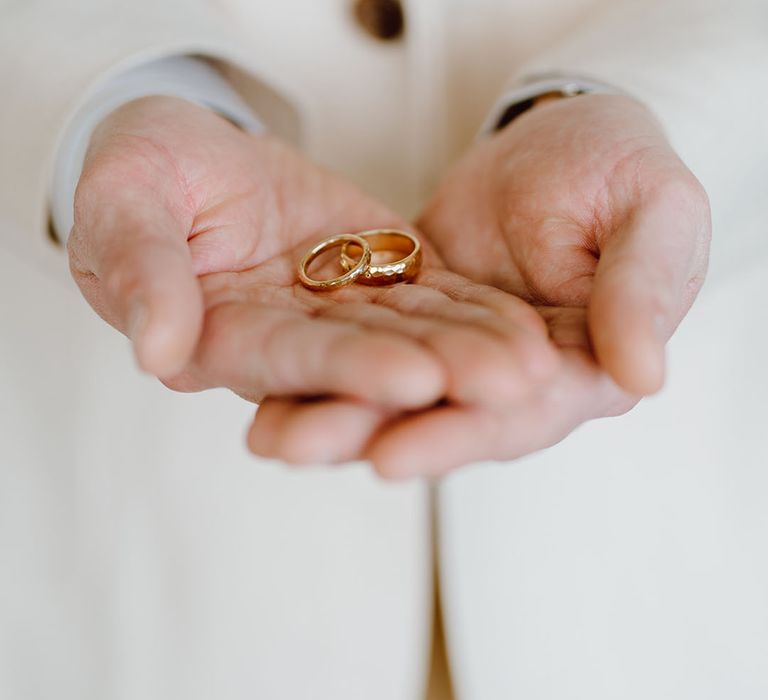 Groom holding the gold wedding bands