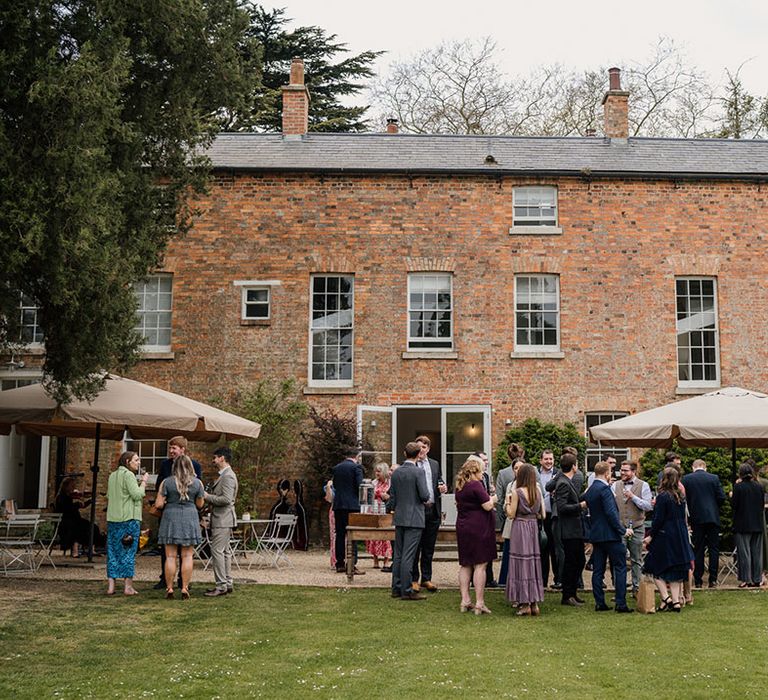 Wedding guests mingle and drink outside of the Aswarby Rectory wedding venue 